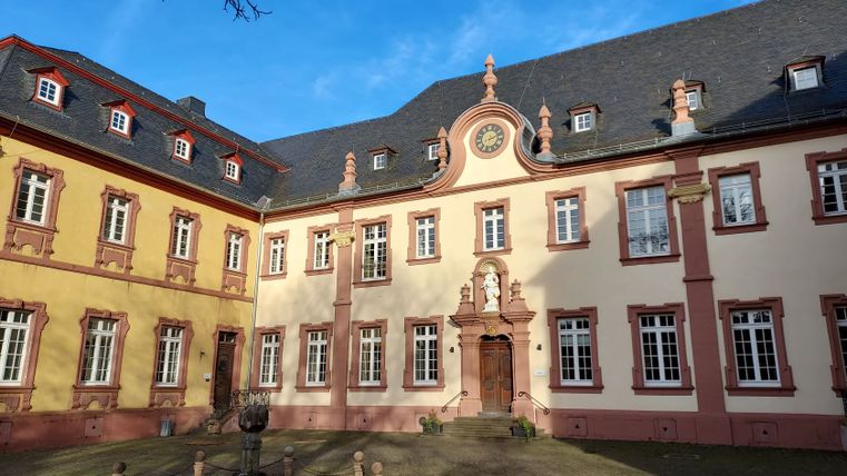 Innenhof des Klosters Steinfeld mit barocker Fassade und Uhr.
