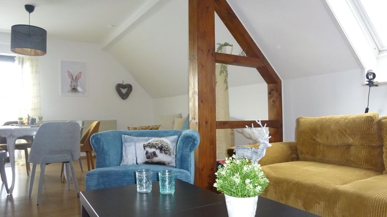 Eine gemütliche Wohnung mit modernen Möbeln und einer hellen, einladenden Atmosphäre. Die Einrichtung umfasst blaue und braune Sofas, einen schwarzen Tisch und einen Essbereich im Hintergrund.