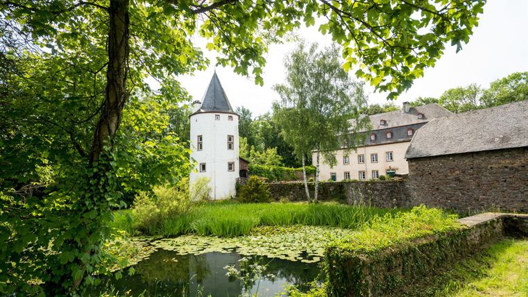 Ein malerischer Ort mit einem weißen Turm und einem schönen Teich. Umgeben von üppigem Grün und historischen Gebäuden.