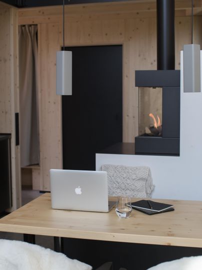 Ein moderner Arbeitsplatz mit einem Laptop auf einem Holztisch. Im Hintergrund befindet sich ein eleganter Kamin und eine ruhige, gemütliche Atmosphäre.