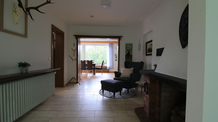 Ein heller Flur mit einem gemütlichen Sessel und Blick auf einen Essbereich. An den Wänden hängen einige dekorative Elemente.