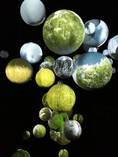 Bunte schwebende Kugeln mit Projektionsbildern von Natur und Landschaften. Die Installation schafft eine faszinierende Atmosphäre.