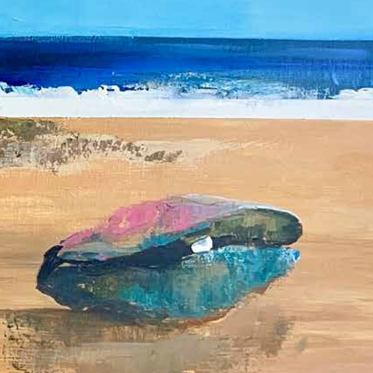 Eine bunte Muschel liegt am Strand. Im Hintergrund sieht man das Meer und den blauen Himmel.
