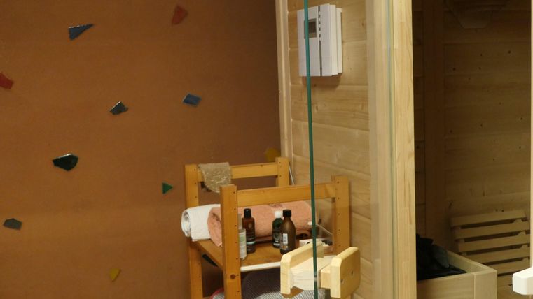Ein gemütlicher Saunabereich mit Holzregalen und Pflegeprodukten. Die Wände sind mit bunten Steinen dekoriert.