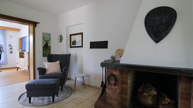 Ein gemütlicher Wohnraum mit einem Sessel, einem Kamin und modernen Dekorationen. Helle Wände und ein zugänglicher Raum schaffen eine einladende Atmosphäre.