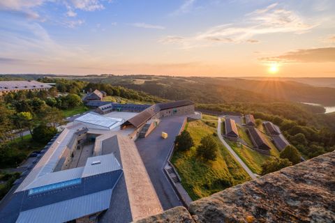 Eine atemberaubende Landschaft mit modernen Gebäuden und sanften Hügeln. Der Sonnenuntergang sorgt für eine malerische Stimmung.