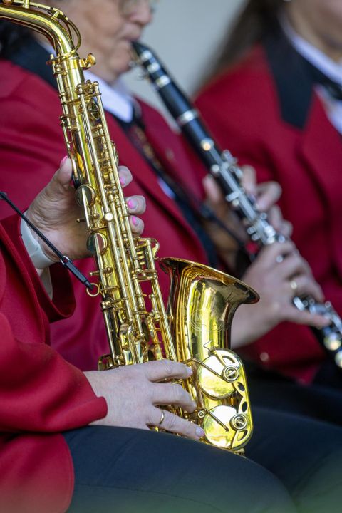 Musiker in roten Jacken spielen verschiedene Holzblasinstrumente. Im Vordergrund ist ein Saxophon zu sehen.