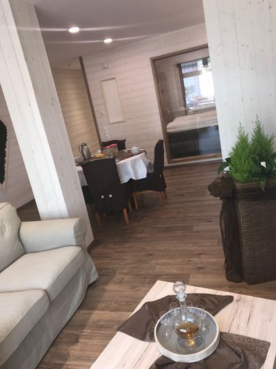 Ein einladendes Wohnzimmer mit einem bequemen Sofa und einem Tisch im Essbereich. Der Raum hat helle Wände und warmen Holzfußboden, der eine gemütliche Atmosphäre schafft.