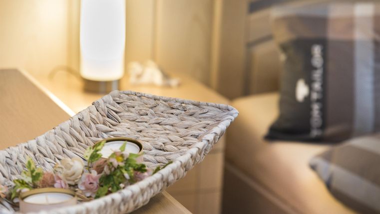 Ein stilvoller Nachttisch mit einem Korb und dekorativen Blumen. Neben dem Korb steht eine sanfte Lampe, die eine gemütliche Atmosphäre schafft.