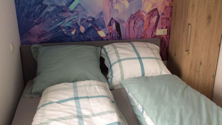 Ein gemütliches Zimmer mit zwei Betten und einer bunten Wandgestaltung. Die Bettwäsche ist hellblau und gestreift.