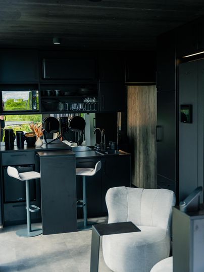 Eine moderne Küche mit eleganten Möbeln und einem minimalistischen Design. Großzügige Fenster lassen viel Licht herein und bieten einen Blick ins Grüne.