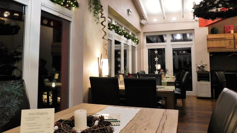 Ein gemütliches Restaurant mit festlicher Dekoration. Die Tische sind schön gedeckt und das Licht sorgt für eine einladende Atmosphäre.