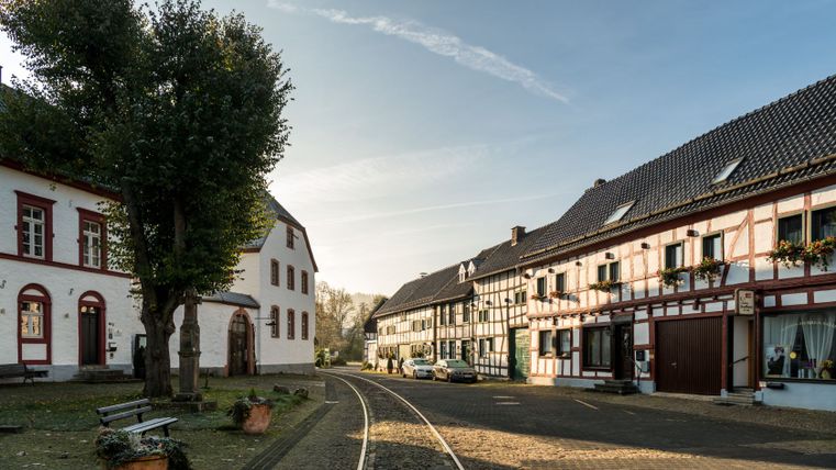 Marktplatz in Olef mit Fachwerkhäusern und Schienen der Oleftalbahn.