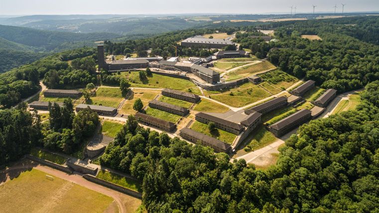 Eine beeindruckende Festung umgeben von üppigem Grün. Die Struktur erstreckt sich über einen Hügel und bietet einen weiten Blick auf die Landschaft.