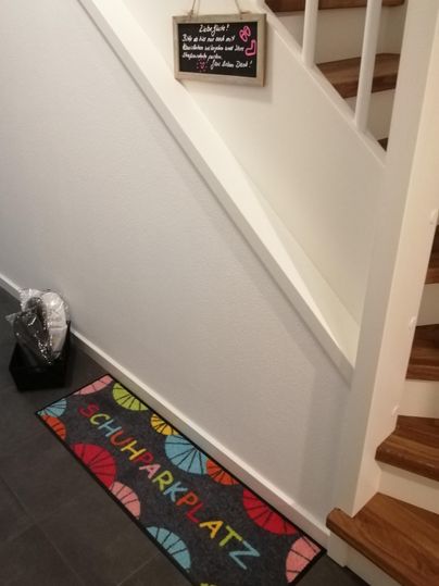 Ein attraktiver Eingang mit einem bunten Teppich und einer Treppe. Auf einer Tafel steht eine freundliche Willkommensnachricht.