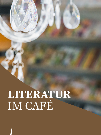 Ein eleganter Kronleuchter mit Kristallen hängt im Café. Im Hintergrund sind Bücherregale sichtbar, die eine gemütliche Atmosphäre schaffen.