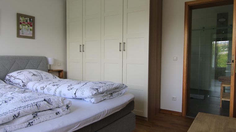 Ein gemütliches Schlafzimmer mit einem Doppelbett und einem großen Kleiderschrank. Im Hintergrund ist ein Badezimmer sichtbar.