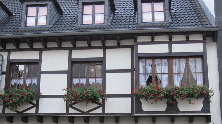 Ein traditionelles Fachwerkhaus mit mehreren Fenstern. Die Fenster sind mit Blumenkästen geschmückt.