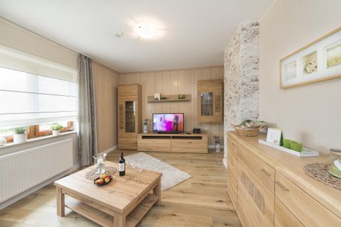 Ein modernes Wohnzimmer mit hellem Holz und eleganten Möbeln. Der Raum verfügt über einen Fernseher und eine gemütliche Atmosphäre.