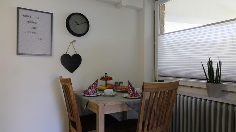 Ein gemütlicher Essbereich mit einem Tisch und Stühlen. Auf dem Tisch steht Geschirr sowie eine kleine Dekoration.