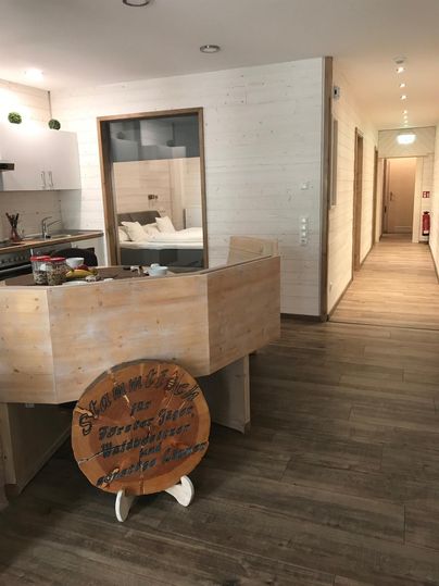 Ein modernes Interieur mit einem Holzschalter und einem langen Flur. Die Wände sind hell und der Boden ist aus Holz.