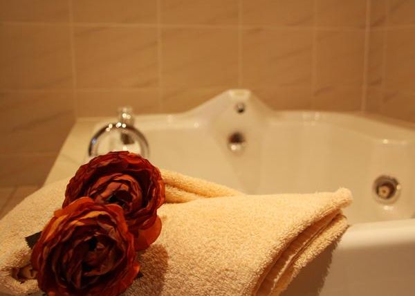 Ein gemütliches Badezimmer mit einer Badewanne und frischen Handtüchern. Rote Rosen verleihen der Szene eine elegante Note.