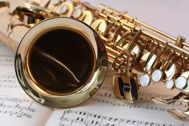 Musiker in roten Jacken spielen verschiedene Holzblasinstrumente. Im Vordergrund ist ein Saxophon zu sehen.