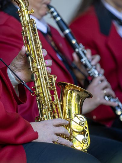 Musiker in roten Jacken spielen verschiedene Holzblasinstrumente. Im Vordergrund ist ein Saxophon zu sehen.