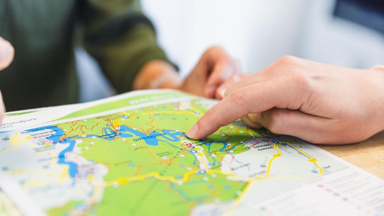 Deux personnes regardent une carte. Une main pointe vers un certain point sur la carte.