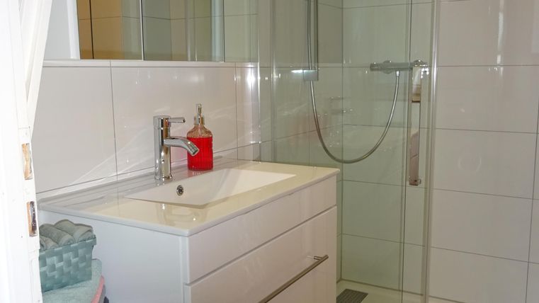 Ein modernes Badezimmer mit einer Dusche aus Glas und einem stilvollen Waschbecken. Der Boden ist mit bunten Fliesen dekoriert.