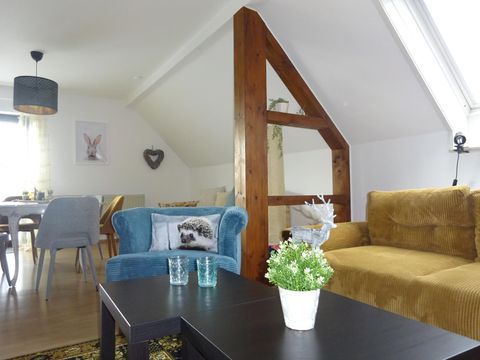 Eine gemütliche Wohnung mit modernen Möbeln und einer hellen, einladenden Atmosphäre. Die Einrichtung umfasst blaue und braune Sofas, einen schwarzen Tisch und einen Essbereich im Hintergrund.