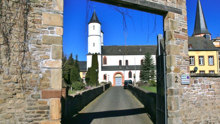 Ein historisches Gebäude mit einer charakteristischen weißen Türmchen und einer schönen Mauer. Der klare blaue Himmel verleiht der Szene einen freundlichen Ausdruck.