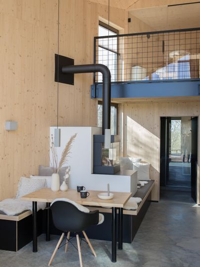 Eine moderne Innenansicht mit holzverkleideten Wänden und einer offenen Gestaltung. Ein gemütlicher Essbereich mit einem Tisch und Stühlen ist gut beleuchtet durch das Tageslicht.