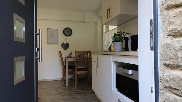 Eine moderne Küche mit einem Esstisch und Stühlen. Der Raum ist hell und freundlich, mit Holzboden und Pflanzen.