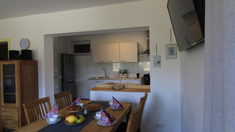 Eine helle Küche mit einem gemütlichen Essbereich. Der Tisch ist liebevoll gedeckt und frisches Obst steht bereit.