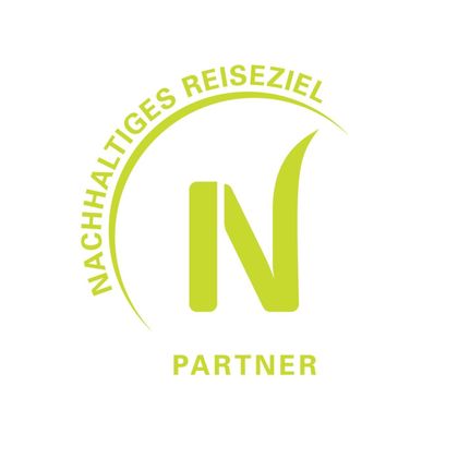 A logo that represents sustainable travel destinations. It features the letter "N" and the words "Sustainable Travel Destination" as well as "Partner".